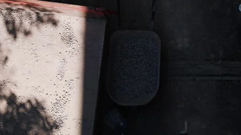 Construction worker picks up crushed stone from the ground with a shovel and Vidéo 341470054