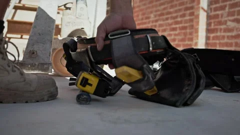Construction worker picks up a tool belt from the floor of a building site Stock Footage 337243065