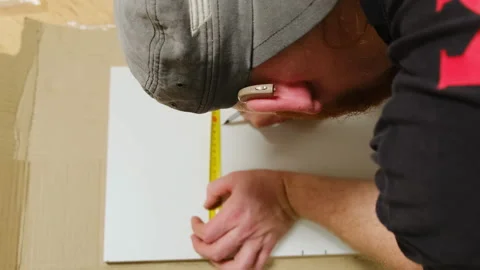 Construction worker places measuring tape along length of board Video stock 304402207