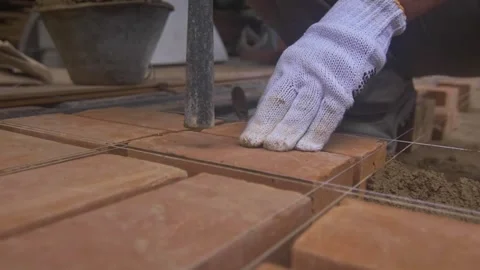 Construction worker placing brick on cement in order to build a brick floor 스톡 동영상 255684414