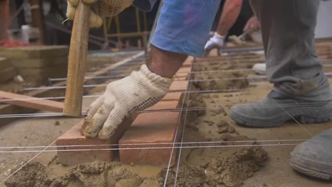Construction worker placing brick on cement in order to build a brick pavement Stock Footage 255684462