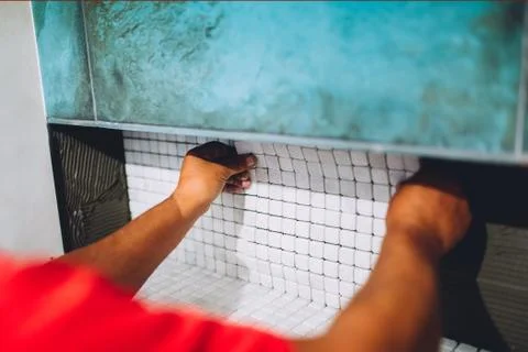Construction worker placing ceramic mosaic boards on flexible adhesive Stock Photos