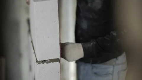 Construction worker placing concrete block on mortar wall Stock Footage 323870516