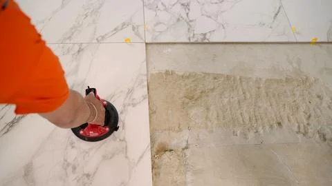 Construction worker placing marble tile using suction cup tool Stock Photos