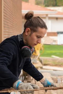 Construction worker placing a rusty iron mesh in outdoors construction place Stockfoto's