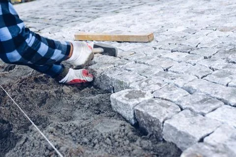 Construction worker placing stone tiles for pavement, terrace Foto stock