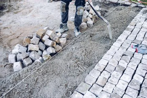Construction worker placing stone tiles for pavement, terrace Fotos Stock