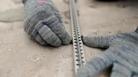 Construction worker placing tile leveling system clips on metal profile Stock Photos