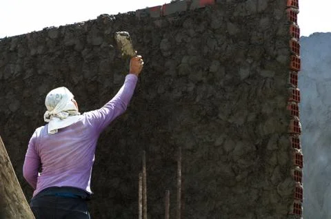 Construction worker - plastering and smoothing concrete wall with cement by a Stock Photos