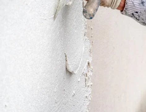 Construction worker plastering and smoothing concrete wall with cement Stock-Fotos