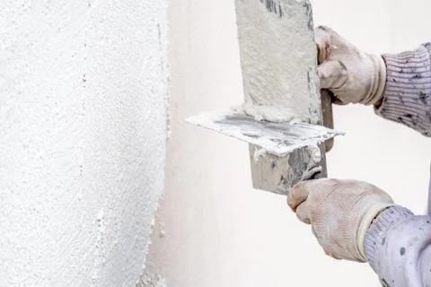 Construction worker plastering and smoothing concrete wall with cement Stock Photos