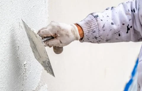 Construction worker plastering and smoothing concrete wall with cement Stock-Fotos