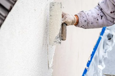Construction worker plastering and smoothing concrete wall with cement Stock Photos