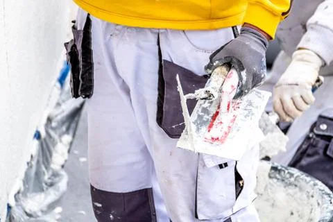 Construction worker plastering and smoothing concrete wall with cement Stock Photos