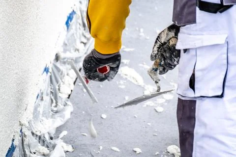 Construction worker plastering and smoothing concrete wall with cement Stock Photos