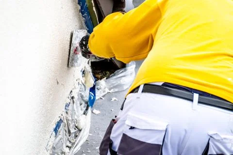 Construction worker plastering and smoothing concrete wall with cement Stock Photos