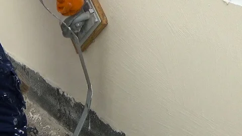 Construction worker plastering a wall with American trowel in hand Stock Footage 84835008