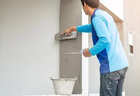 Construction worker plastering a wall with a spatula. Stock Photos