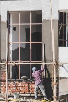 Construction worker plastering window panel ledge during residential house .. Stock Photos