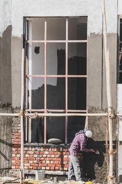 Construction worker plastering window panel ledge during residential house .. Stock Photos