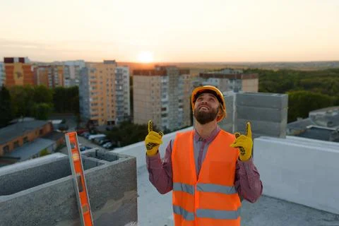 Construction worker pointing upwards at building site with cranes and citysca Stock Photos