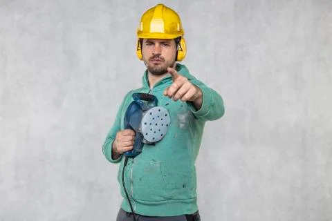 The construction worker points his finger at you, the grinder in his hand Foto stock