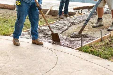 Construction Worker Pooring Wet Deck Cement Into Wooden Frame Foto stock