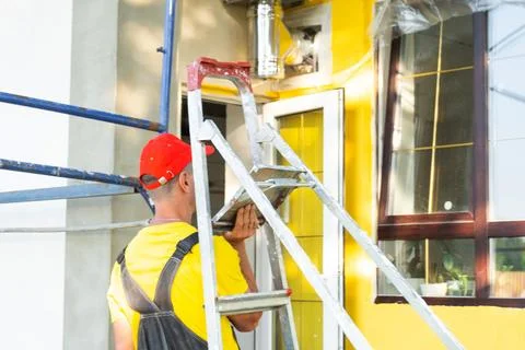 Construction worker portrait with ladder in front of house, home repair pro.. Stock Photos