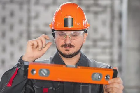 Construction worker portrait with level tool, caucasian bearded man in hard hat Stock Photos