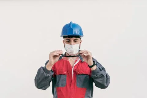 Construction worker portrait on white wall posing with face mask Stock Photos