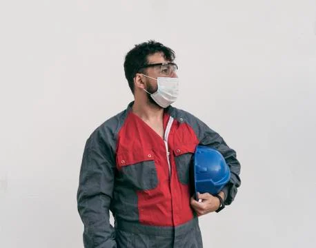 Construction worker portrait on white wall posing with face mask Stock-Fotos