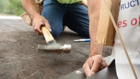 Construction Worker Pounding in Nail with Hammer on Flat Rooftop Closeup Stock Footage 104889948