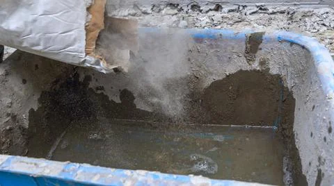Construction worker pouring the cement to the bucket. Adhesive mixing. Waitin Stock Photos
