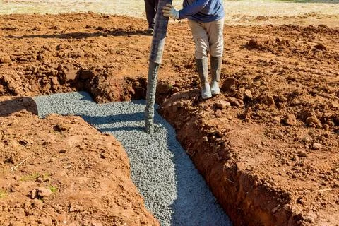 Construction worker is pouring cement concrete by using an automatic pump to lay Stock Photos