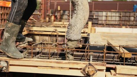 Construction worker pouring concrete into building foundation formwork Stock Photos