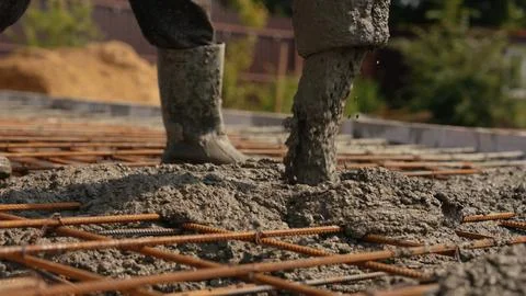 Construction worker pouring concrete on building foundation Stock Photos