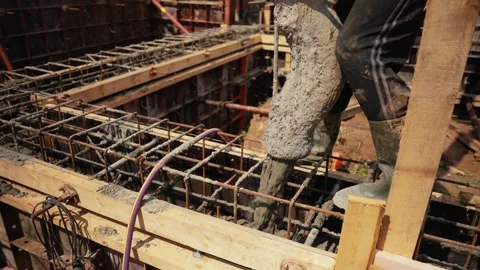Construction worker pouring concrete into foundation formwork Stock Footage 341294823