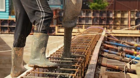 Construction worker pouring concrete into foundation rebar frame Stock Photos