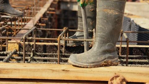Construction worker pouring concrete into foundation rebar structure Stock Photos