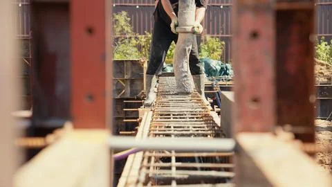 Construction worker pouring concrete into foundation rebar structure Stock Photos
