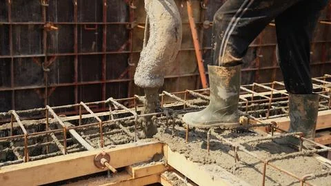 Construction worker pouring concrete into foundation structure Stock Photos