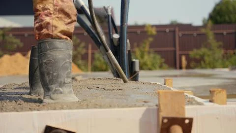 Construction worker pouring concrete foundation at building site Stock Photos