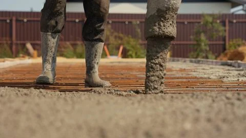 Construction worker pouring concrete on foundation rebar frame Stock Photos