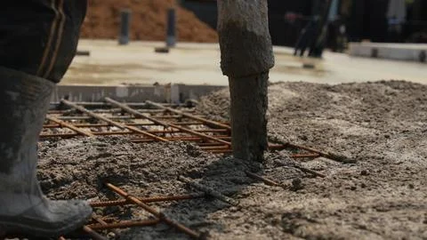 Construction worker pouring concrete foundation at building site Stock Photos