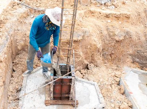A construction worker is pouring concrete manually into a column foundation.. Stock Photos