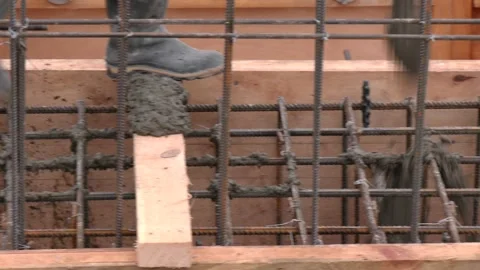 Construction worker pouring concrete onto reinforcing mesh at a building site 스톡 동영상 316516421