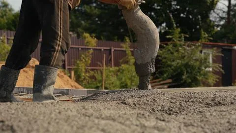 Construction worker pouring fresh concrete for new foundation Stock Photos