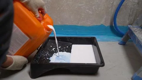 Construction worker pouring primer into a paint tray. Stock Photos