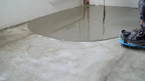 Construction worker pouring self-leveling concrete mix on the floor Stock Photos