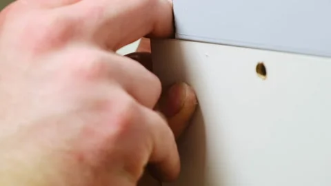 Construction worker prepares to make hole in cabinet panel Stock Footage 304403105